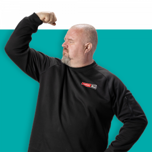Mies seisoo tummassa paidassa ja nostaa käsivartensa voimakkaasti ylös, taustalla on kirkas turquoise väri.